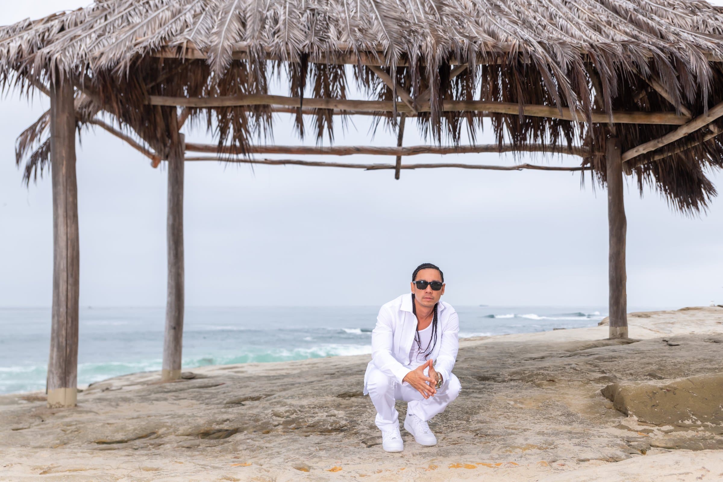 Kekoa crouching under a palapa by the ocean